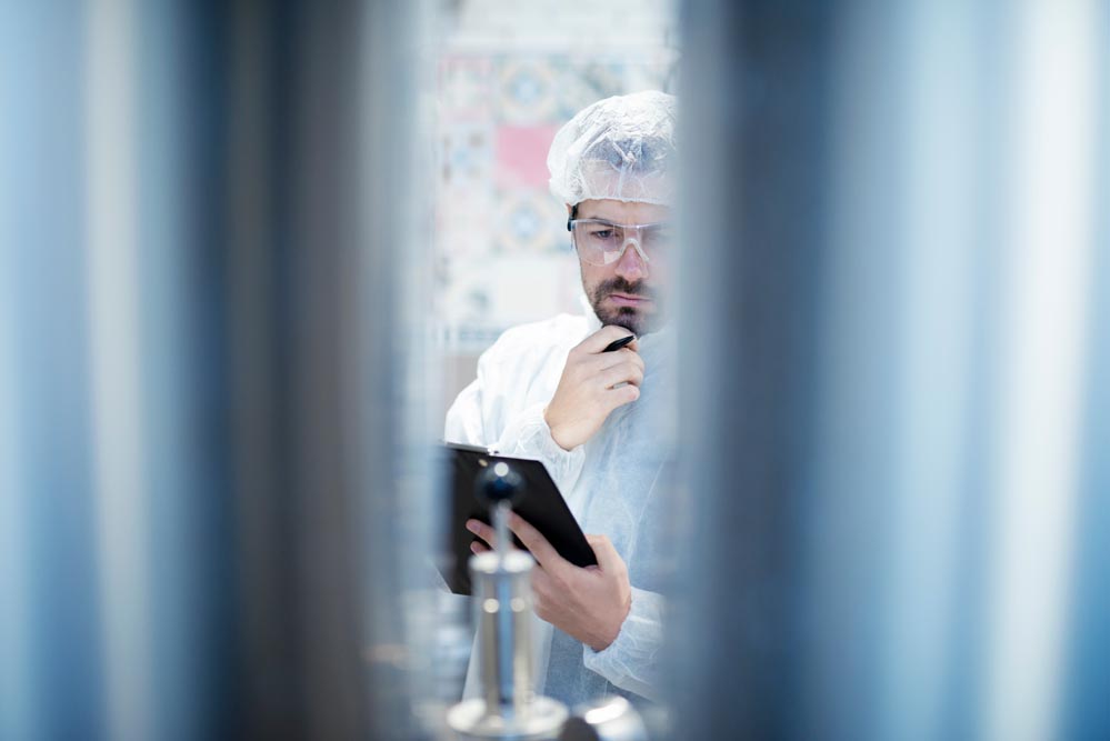 technologist in protective white suit working in food processing